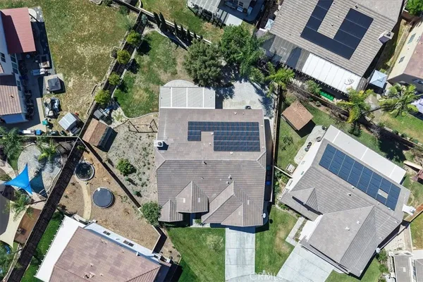 an aerial view of a residential houses with outdoor space and trees