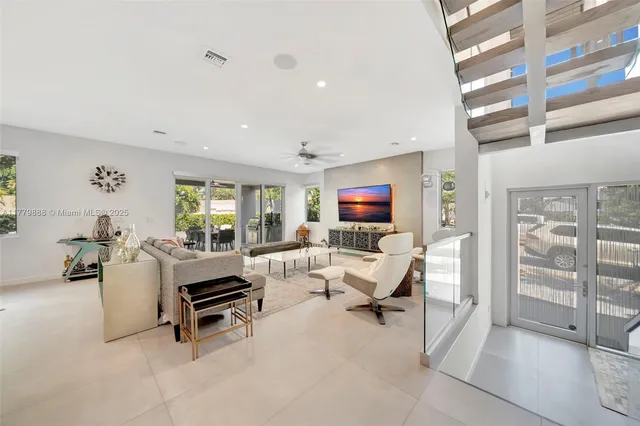 a living room with furniture a flat screen tv and a floor to ceiling window