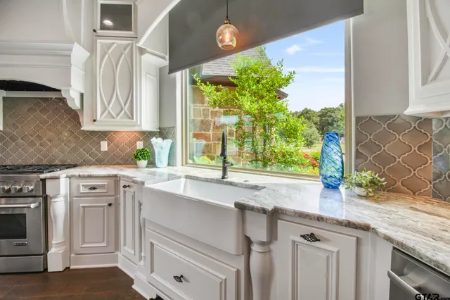 a kitchen with granite countertop a sink a stove and cabinets