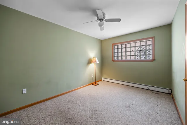 an empty room with chandelier fan and windows