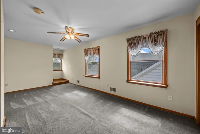 a view of an empty room with window and chandelier fan