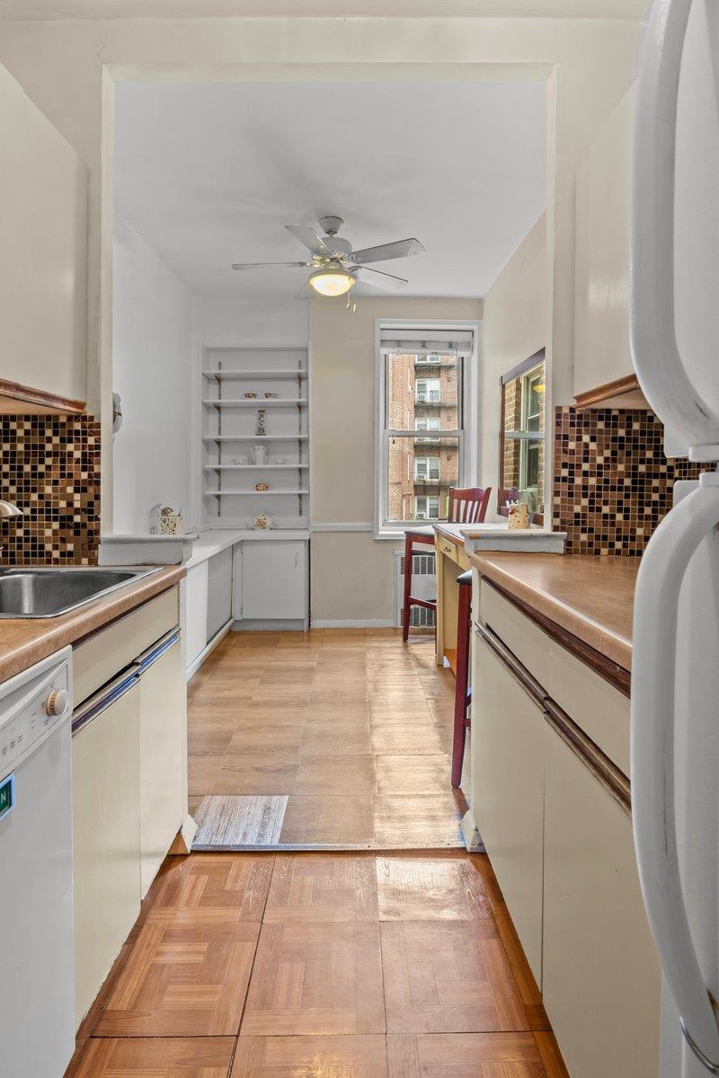 5601 Riverdale Avenue, Unit 5F Bronx, NY 10471 - Photo 14 of 25 a large white kitchen with granite countertop a stove top oven a sink a dining table and chairs