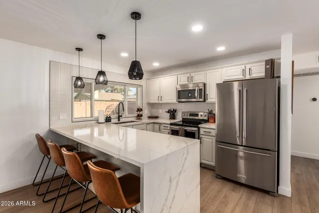 a kitchen with stainless steel appliances granite countertop a refrigerator a sink a stove a dining table and chairs