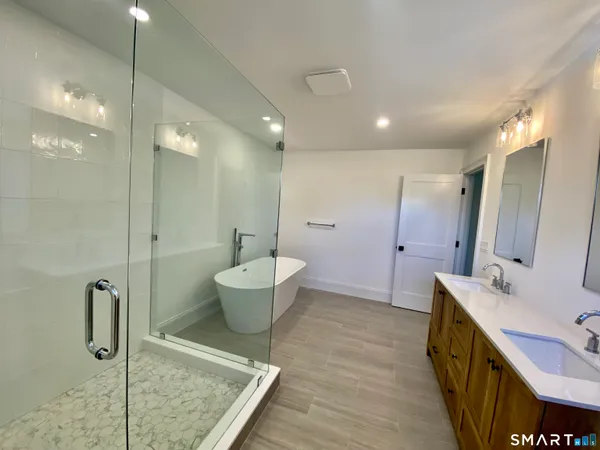a spacious bathroom with a double vanity sink a toilet a mirror and shower