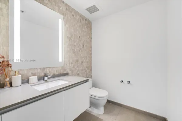 a bathroom with a granite countertop sink a toilet and a mirror