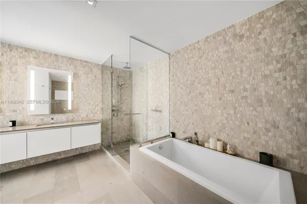 a bathroom with a tub a sink and a large mirror