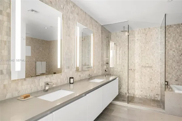 a bathroom with double vanity sinks and a shower