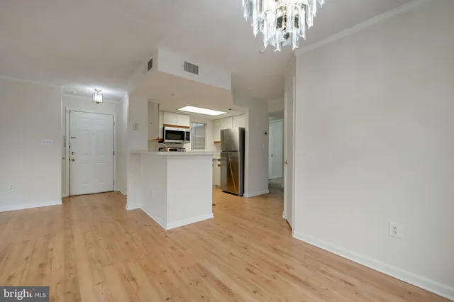 a view of a hallway with wooden floor and a kitchen