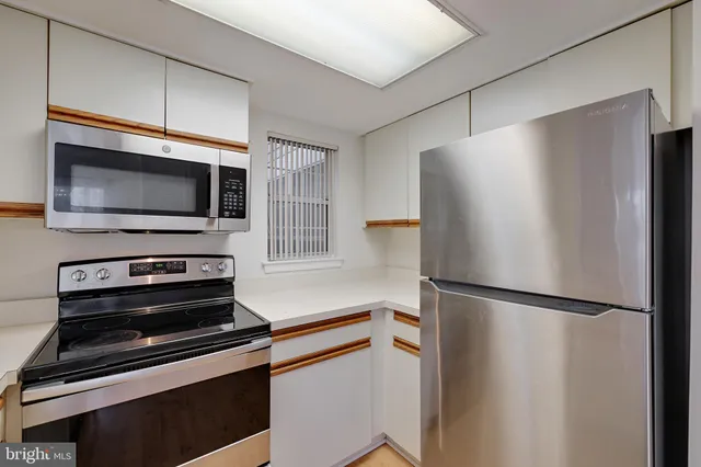 a kitchen with stainless steel appliances granite countertop a sink stove oven and white cabinets with wooden floor