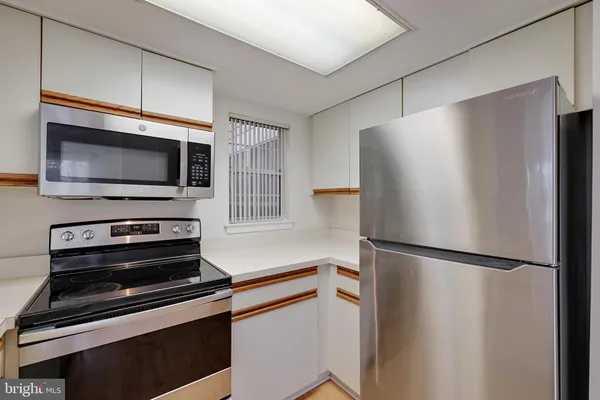 a kitchen with stainless steel appliances granite countertop a sink stove oven and white cabinets with wooden floor