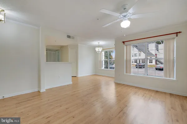 a view of an empty room with a window and wooden floor