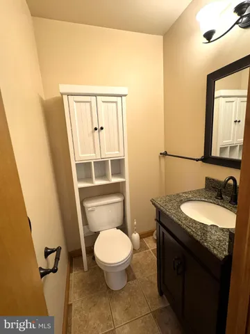 a bathroom with a granite countertop toilet sink and mirror