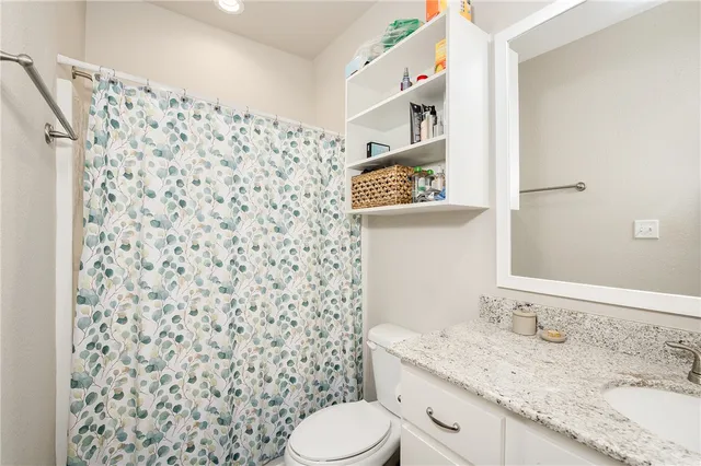 a bathroom with a granite countertop toilet sink and mirror