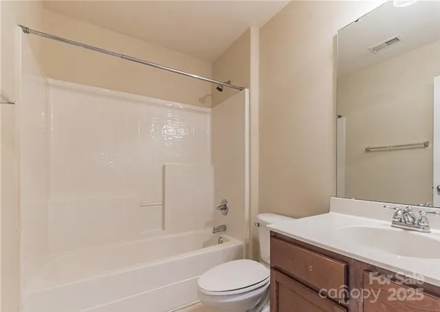 a bathroom with a granite countertop bathtub shower sink vanity and toilet