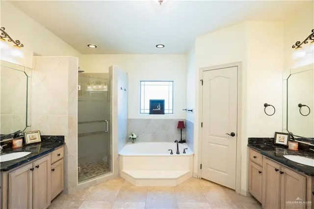 a bathroom with a tub sink double vanity granite and a mirror