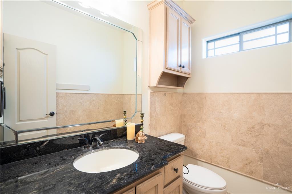 3305 Santa Monica Street Mission, TX 78572 - Photo 17 of 28 a bathroom with a granite countertop sink toilet and a mirror