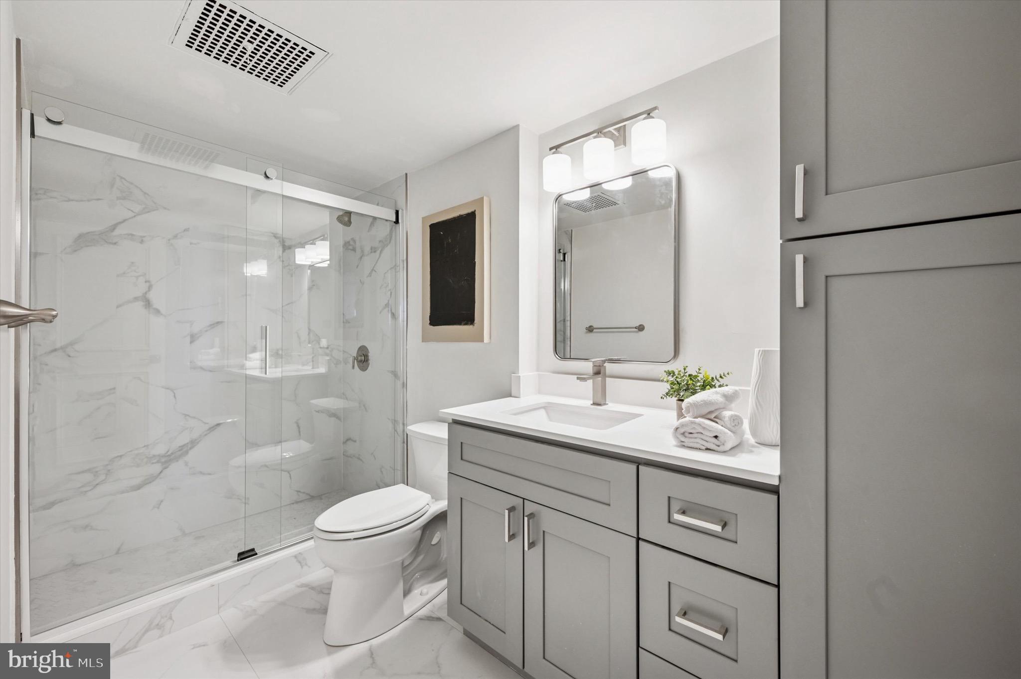 604 South Washington Square, Unit 1015 Philadelphia, PA 19106 - Photo 10 of 24 a bathroom with a toilet a sink a glass door a shower a mirror and vanity