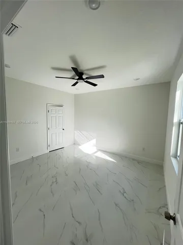 an empty room with a ceiling fan and windows
