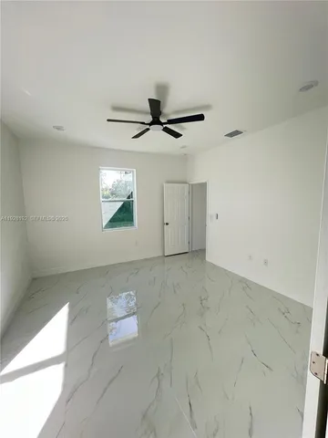 an empty room with windows and ceiling fan