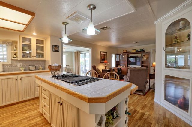a kitchen with a stove a sink a kitchen island with chairs and wooden cabinets