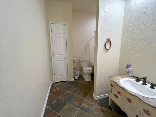 a bathroom with a granite countertop sink mirror vanity and toilet