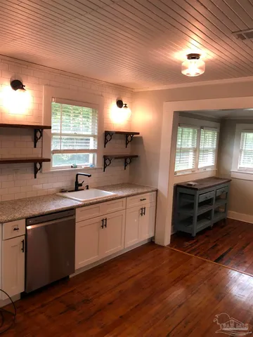 a kitchen with granite countertop a stove a sink and a window
