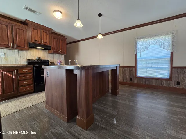 a kitchen with granite countertop a sink a stove and wooden cabinets