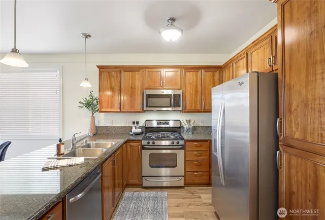 a kitchen with stainless steel appliances granite countertop a refrigerator a stove a sink and a microwave