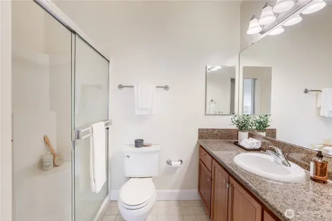 a bathroom with a granite countertop sink a toilet a mirror and shower