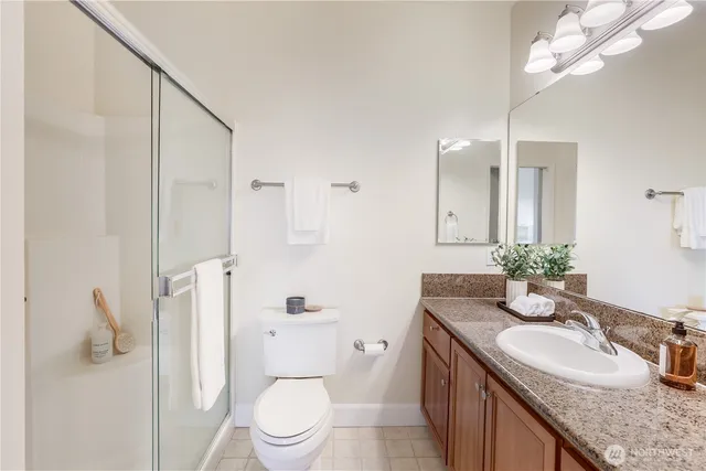 a bathroom with a granite countertop sink a toilet a mirror and shower