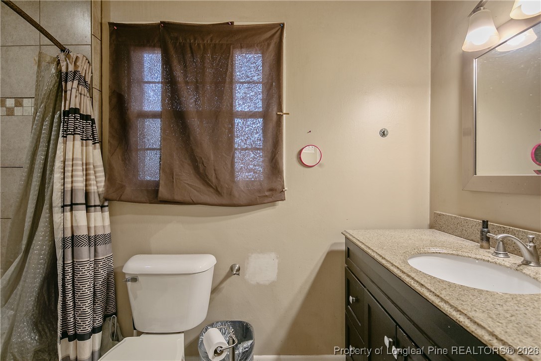 6432 Milford Road Fayetteville, NC 28303 - Photo 30 of 50 a bathroom with a toilet a sink and mirror