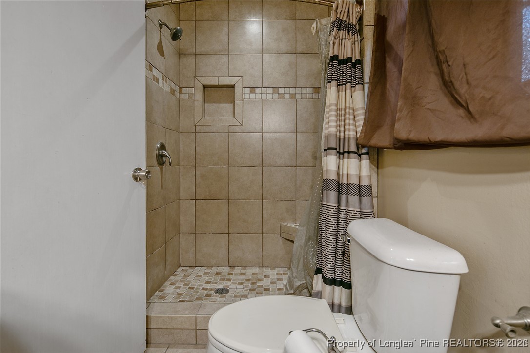 6432 Milford Road Fayetteville, NC 28303 - Photo 32 of 50 a white toilet sitting next to a bathroom sink