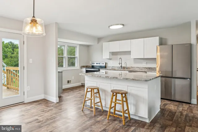 a kitchen with stainless steel appliances granite countertop a stove a refrigerator a sink a dining table and chairs with wooden floor