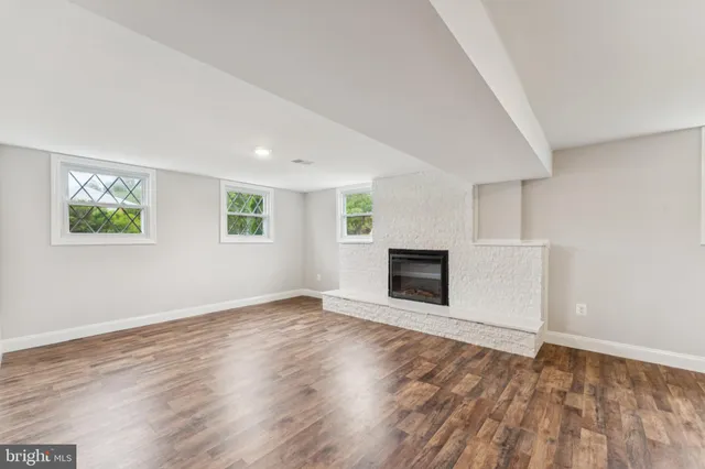 an empty room with wooden floor fireplace and windows