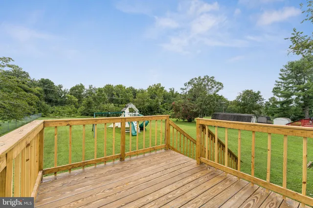 a view of a balcony with wooden floor and fence next to a yard