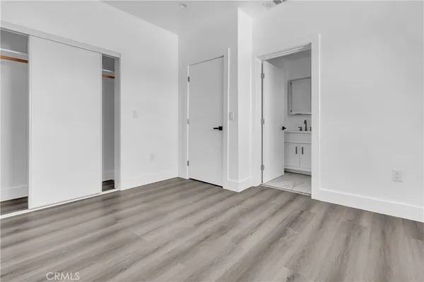a view of an empty room with wooden floor and closet