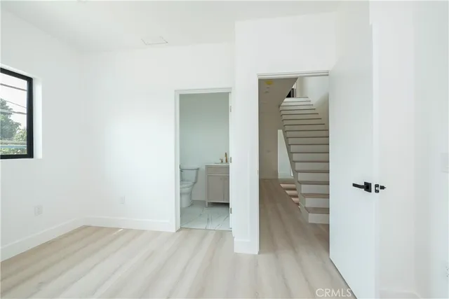 a view of a hallway with wooden floor and a bathroom