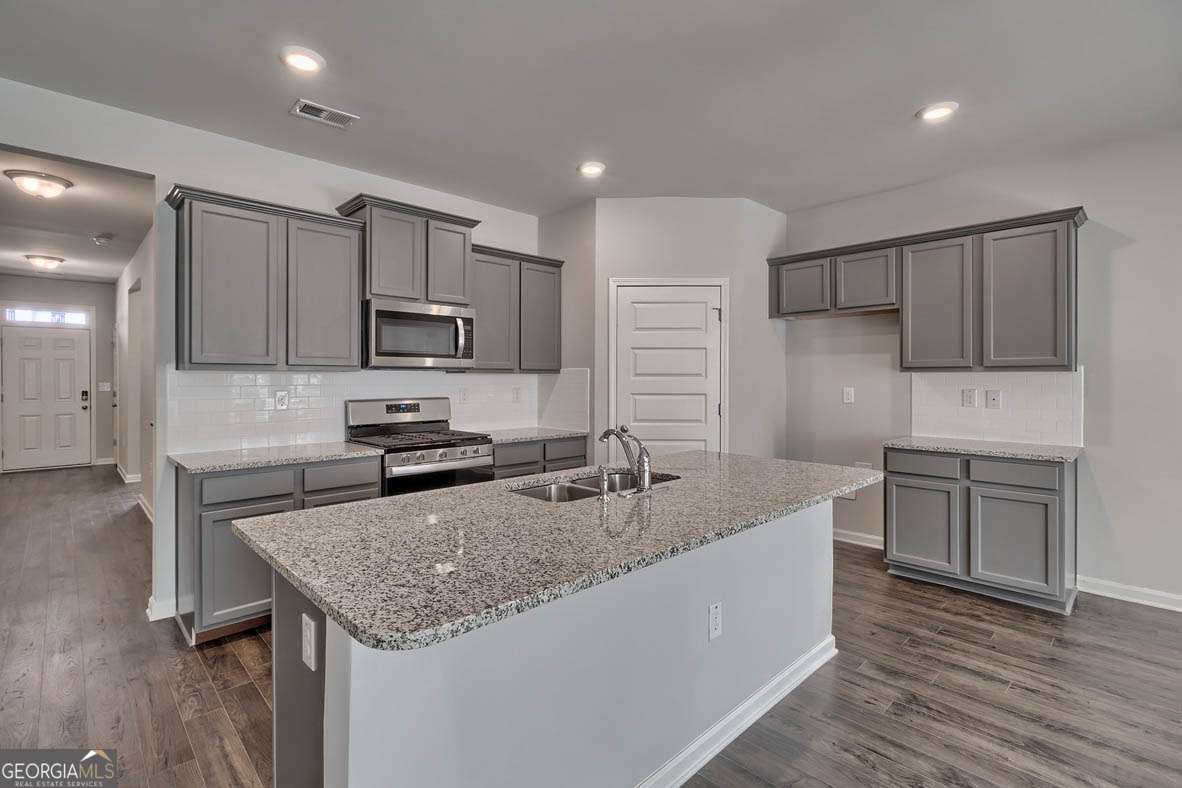 111 Cattle Drive Perry, GA 31069 - Photo 45 of 47 a kitchen with kitchen island granite countertop a sink stove microwave and refrigerator