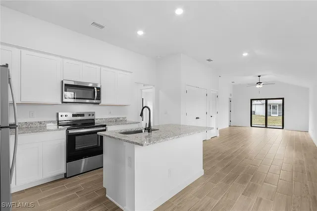 a kitchen with stainless steel appliances granite countertop a sink stove oven and white cabinets with wooden floor