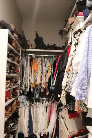 a view of walk in closet with clothes and shoes
