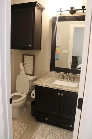 a bathroom with a granite countertop toilet sink and mirror