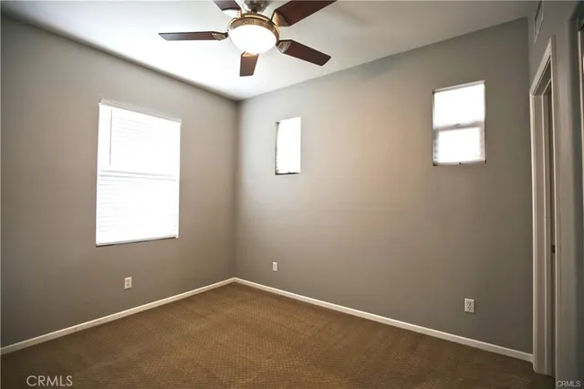 an empty room with a window and a fan