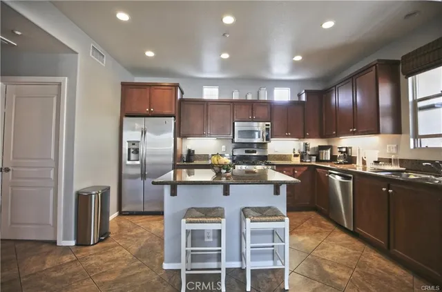 a kitchen with kitchen island granite countertop stainless steel appliances cabinets a sink and a counter top space