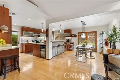 a kitchen with stainless steel appliances kitchen island granite countertop a refrigerator a stove top oven a dining table and chairs with wooden floor