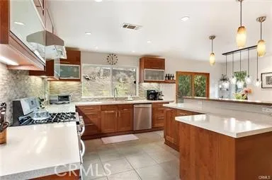 a large kitchen with kitchen island a large counter top space a sink stainless steel appliances and cabinets