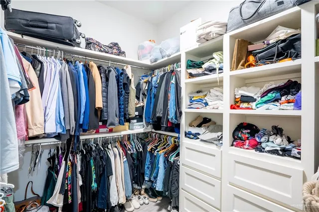 a view of walk in closet with clothes and shoes
