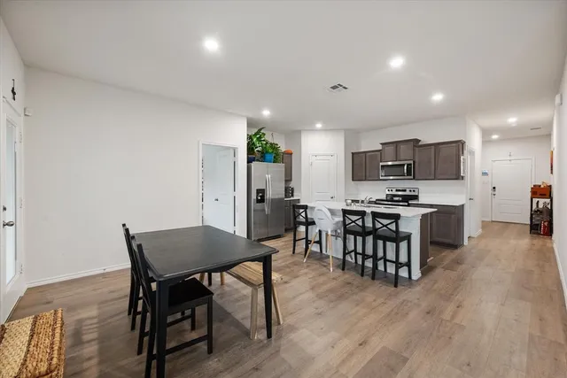 a kitchen with stainless steel appliances a dining table chairs stove refrigerator and cabinets