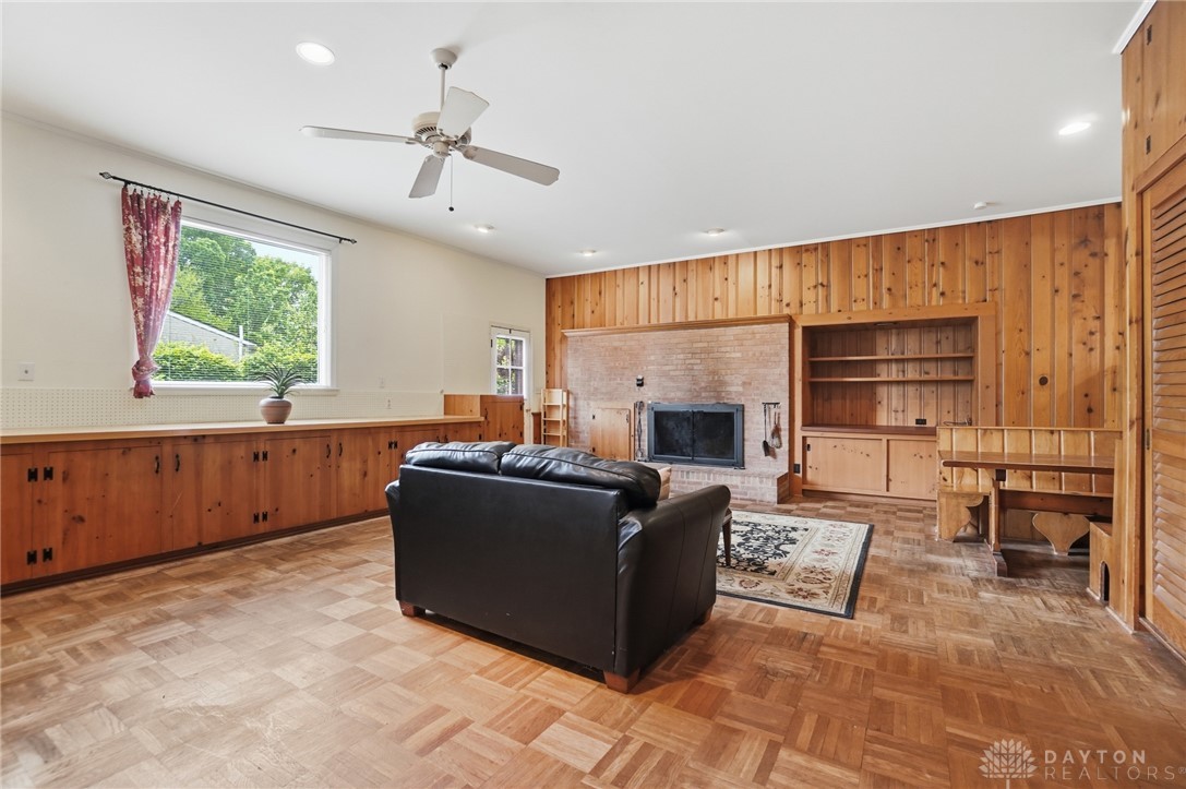 6119 Flemington Road Dayton, OH 45459 - Photo 21 of 76 This inviting living space features warm wood paneling and a classic brick fireplace, creating a cozy ambiance.