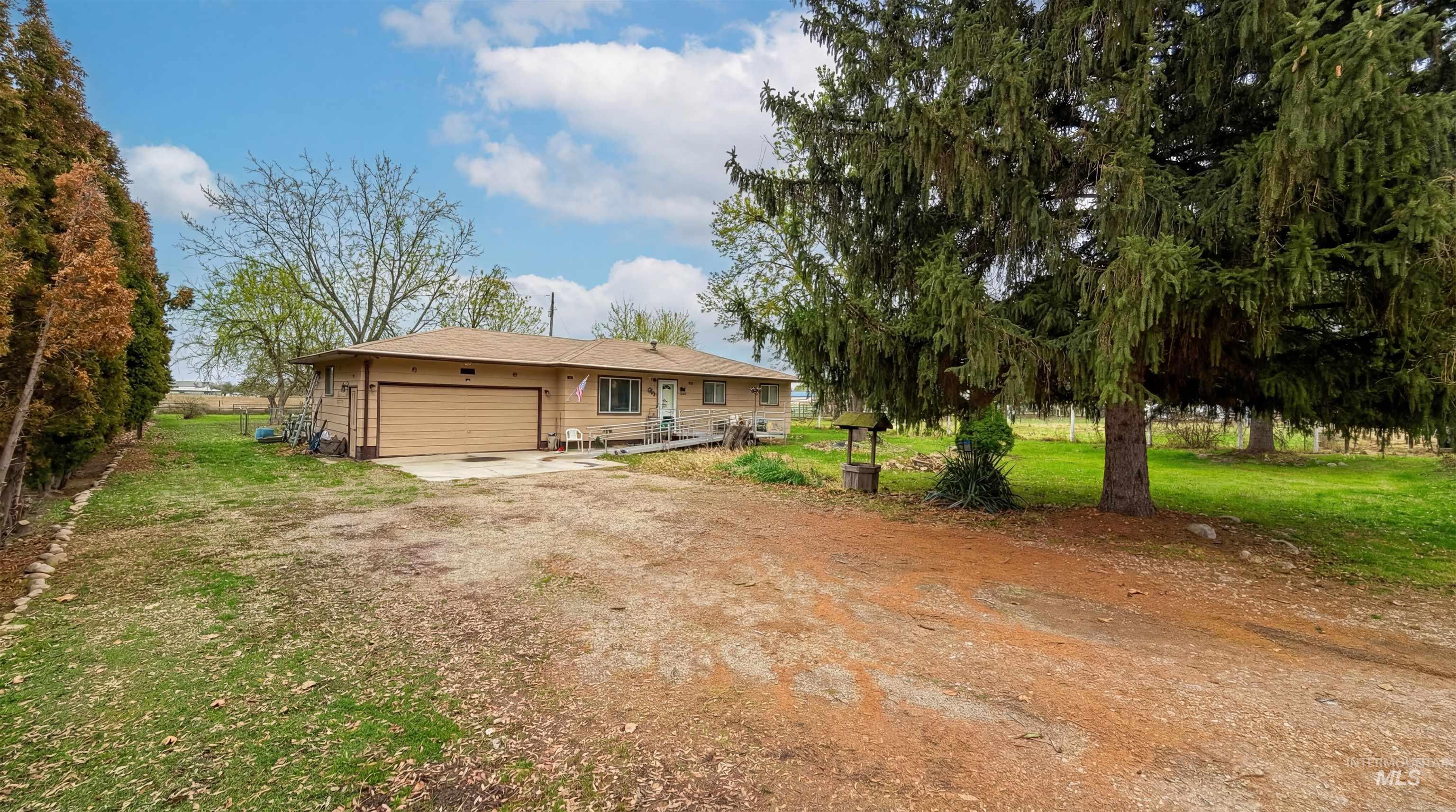 19076 Pleasant Avenue Caldwell, ID 83607 - Photo 3 of 37 View of front of house with a front lawn, dirt driveway, a patio, and an attached garage