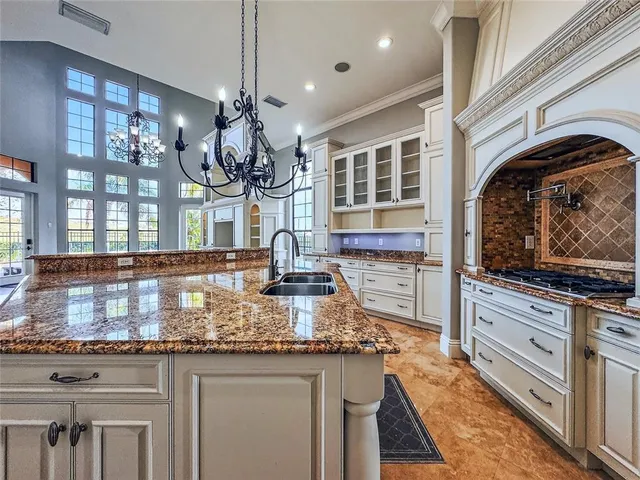 a kitchen with granite countertop a stove a sink and a chandelier